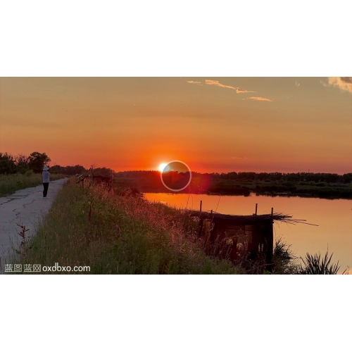 视频湿地湖水边夕阳下拍照录像的女人